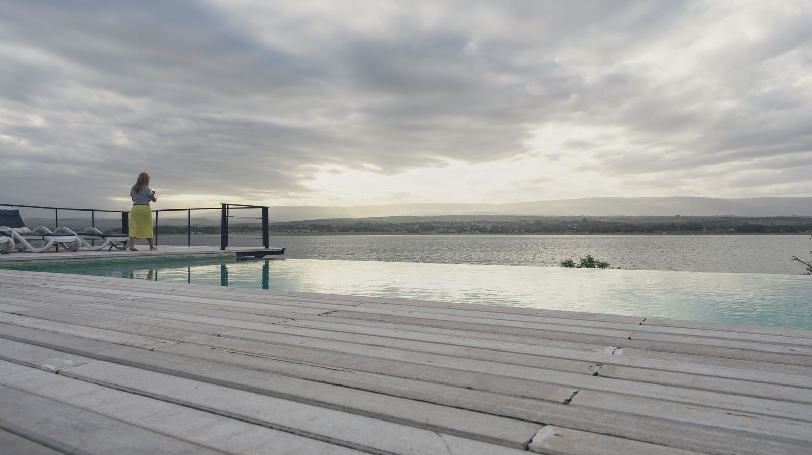 La pileta infinity al atardecer, con el lago encendido