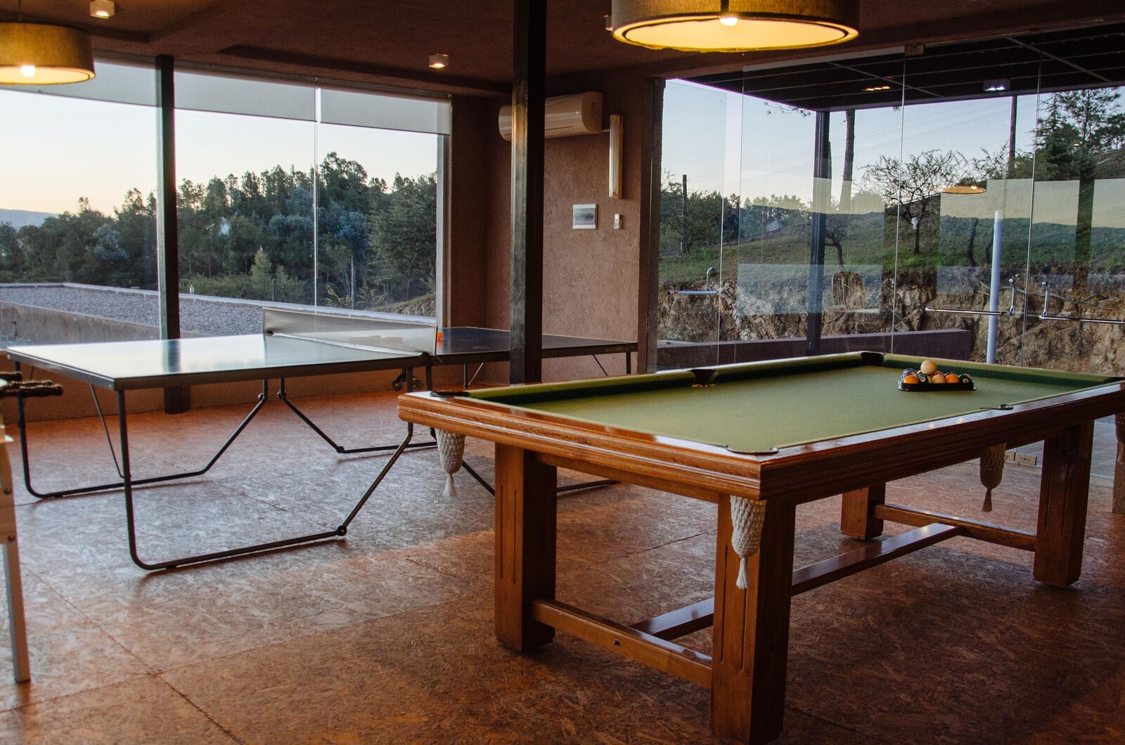 Mesa de pool y mesa de ping pong en la sala de juegos, con ventanales al parque