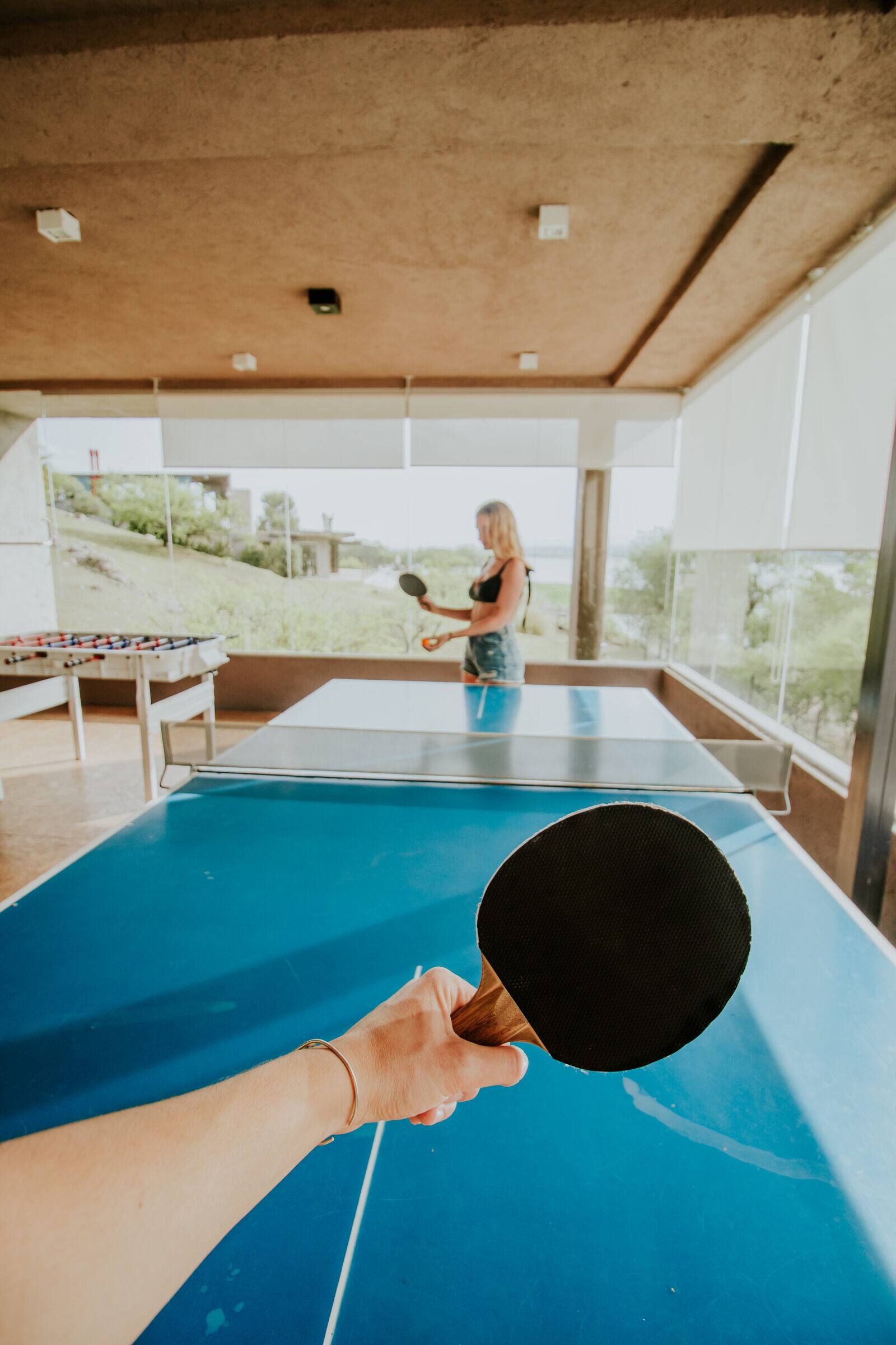 Partido de ping pong en la sala de juegos, con el lago por el ventanal