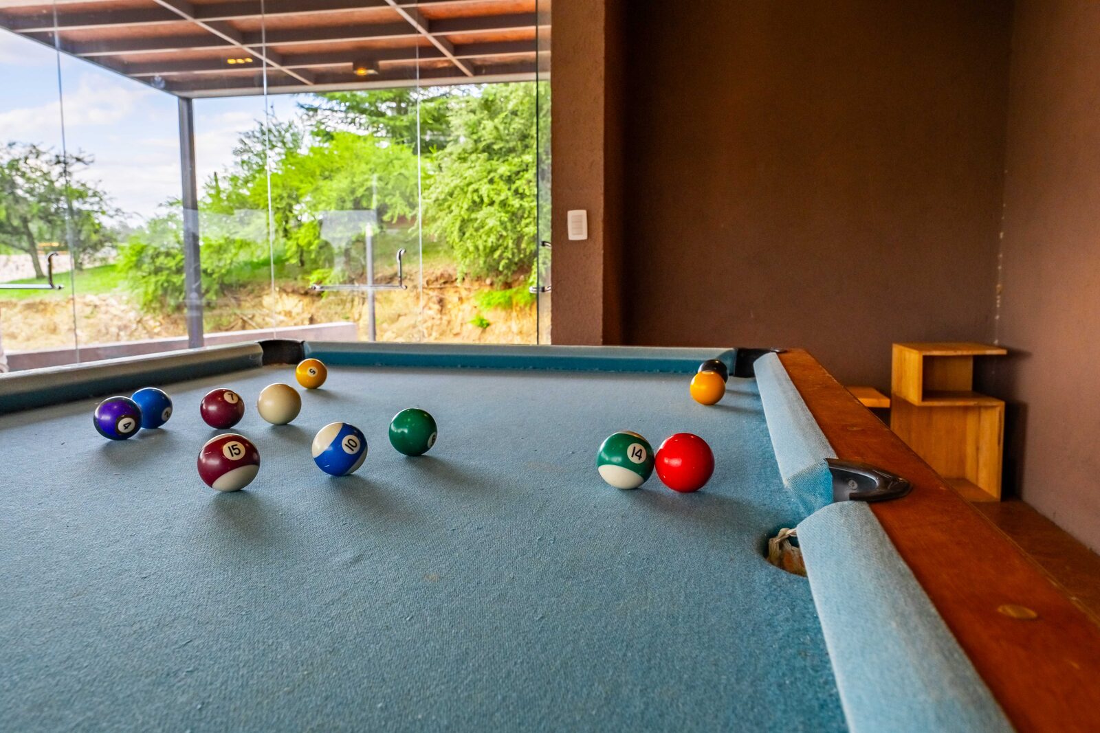 La mesa de pool contra el ventanal, con el lago detrás